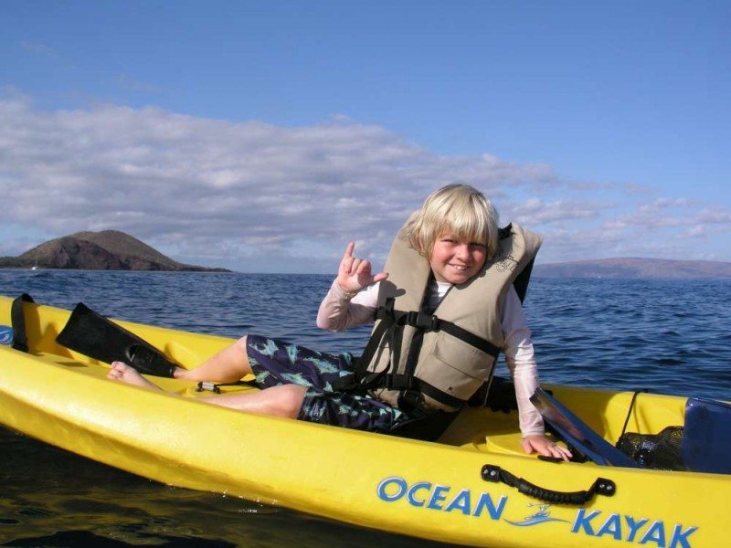 Boy giving shaka on kayak